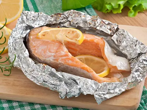 Salmón jugoso cocinado en papel de aluminio con rodajas de limón, perfecto para tus recetas de salmón.